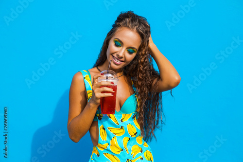 Close-up portrait of a beautiful young amazing girl, on a turquoise background, bright make-up, long hair, perfect healthy skin, face, lady drinks sweet soda, trendy stylish look