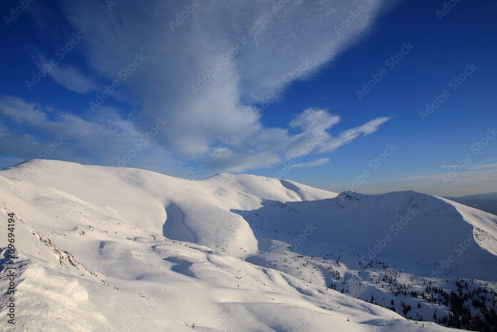 The bright blue sky above the snow-covered slopes of the mountains