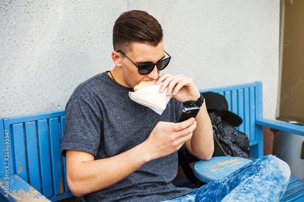 Hipster style guy with a fashionable hairdo. a young man sitting on a bench  in the