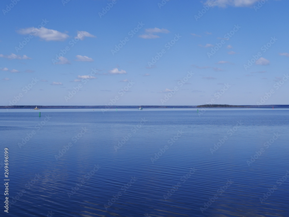 white clouds in the blue sky reflected on the surface of calm water