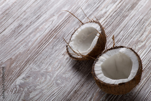 Two halves of coconut on a brown wooden board