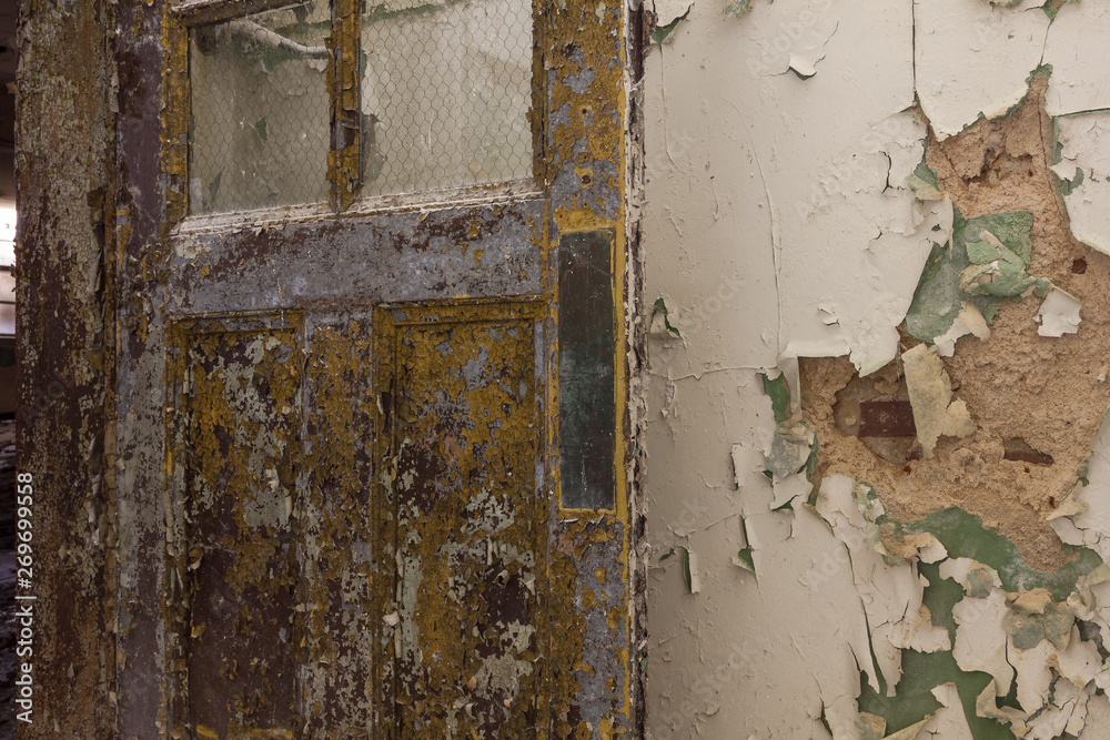 Last remnants of yellow door left open with peeling paint in an abandoned school Last remnants of yellow door left open with peeling paint in an abandoned school