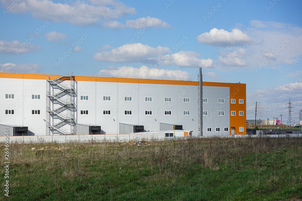 Industrial building, warehouse. Blue sky with clouds. Industrial building, warehouse. Blue sky with clouds.