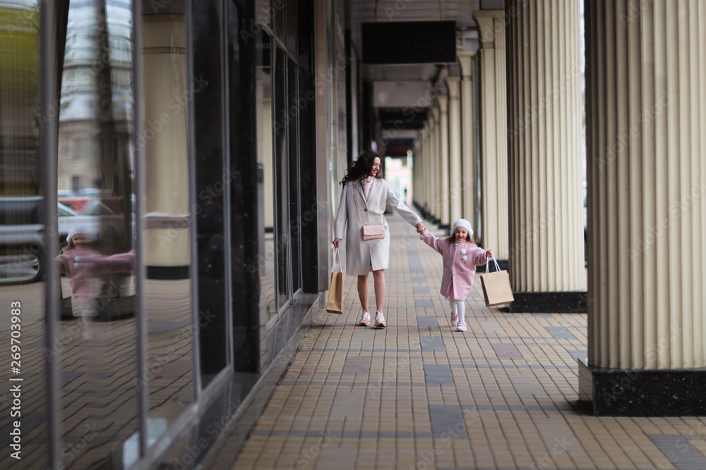 Mom and daughter go shopping down street together