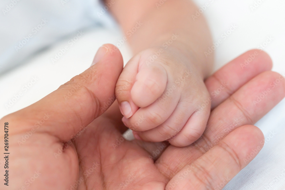 Tiny newborn baby hand on male hands closeup. Happy Family concept. Beautiful conceptual image of Maternity. Tiny newborn baby hand on male hands closeup. Happy Family concept. Beautiful conceptual image of Maternity.