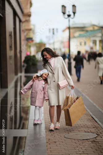 Mom and daughter go shopping down street together © natalialeb