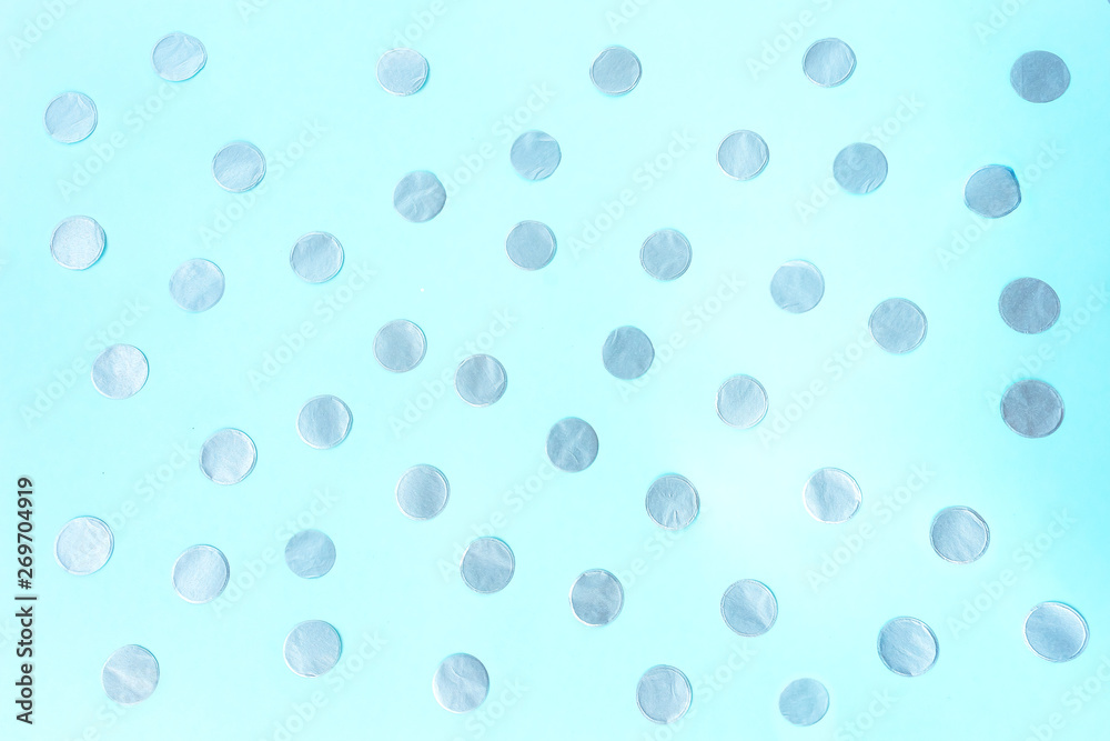 Silvery confetti on a blue background. Festive concept.