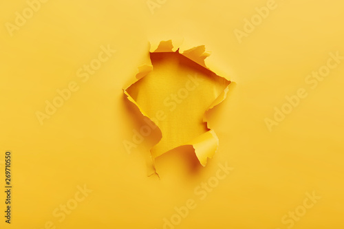 Quadro em tela Small paper hole with torn sides over yellow background for your text, print or promotional content