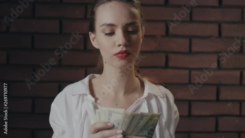 Serious woman counting money banknotes on brick wall. Wealthy businesswoman photo