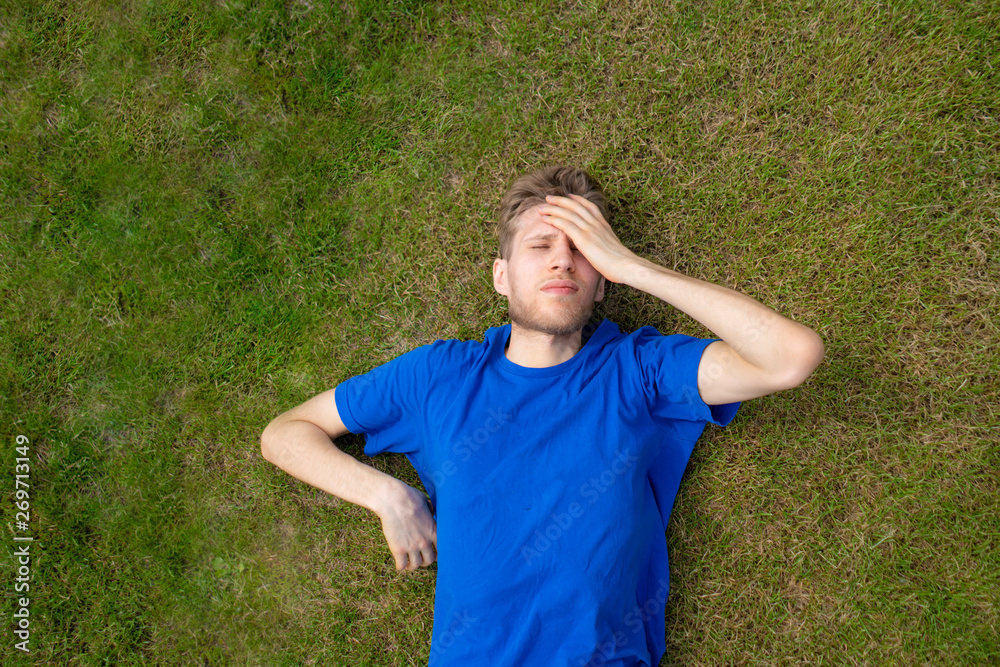 tired male athlete sportsman relax on the grass field after practices tired male athlete sportsman relax on the grass field after practices