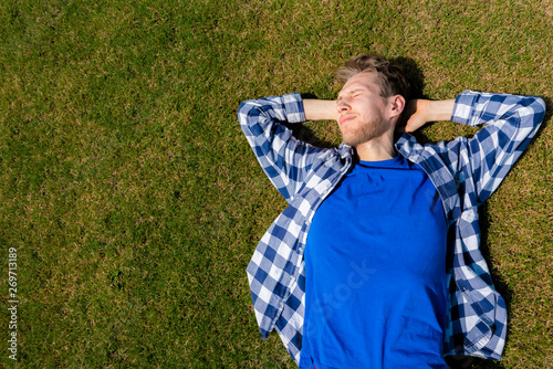 young man relax chill outdoor on the green grass lawn under the summer sunshines