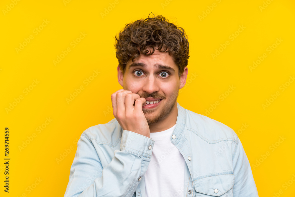 Blonde man over isolated yellow wall nervous and scared Blonde man over isolated yellow wall nervous and scared