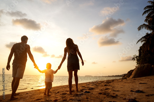 family walk along the beach at sunset with his son, silhouette