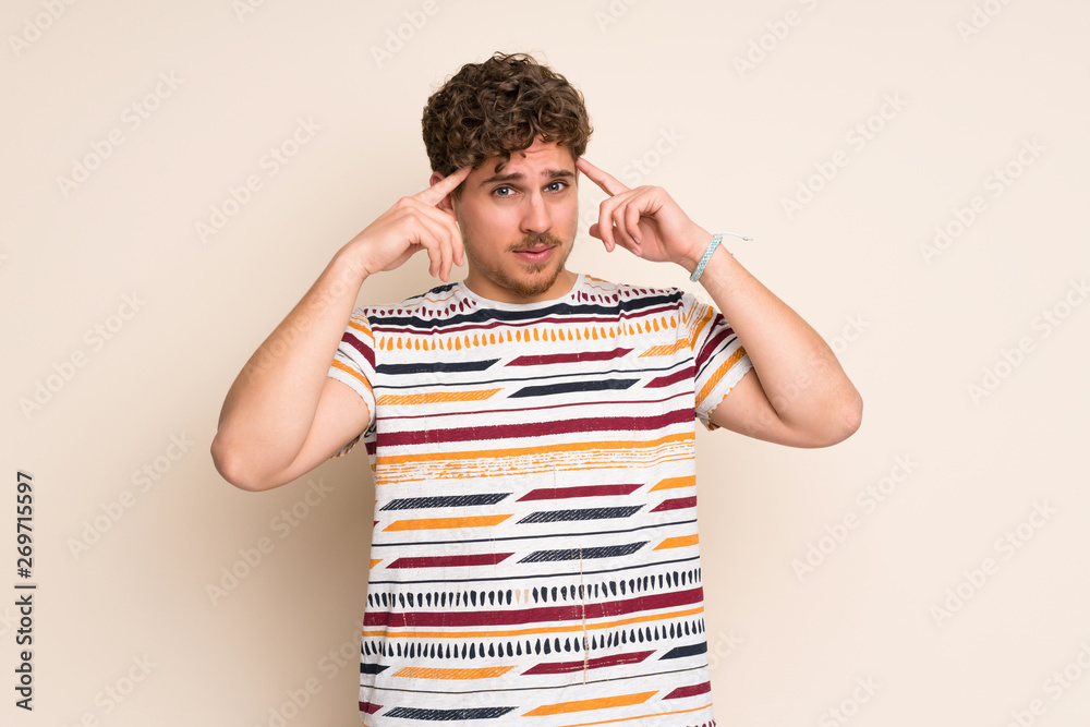 Blonde man over isolated wall having doubts and thinking Blonde man over isolated wall having doubts and thinking