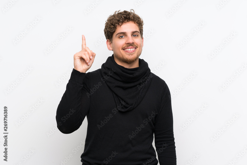Blonde man over isolated white wall showing and lifting a finger in sign of the best Blonde man over isolated white wall showing and lifting a finger in sign of the best