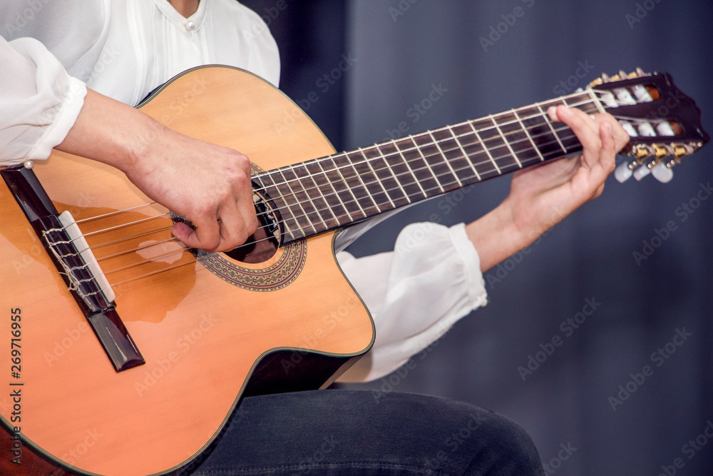 A girl in white shirt playing guitar. Performance at the concert of the guitarist_