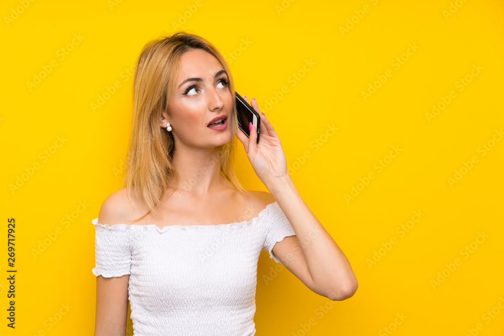 Young blonde woman over isolated yellow wall using mobile phone Young blonde woman over isolated yellow wall using mobile phone