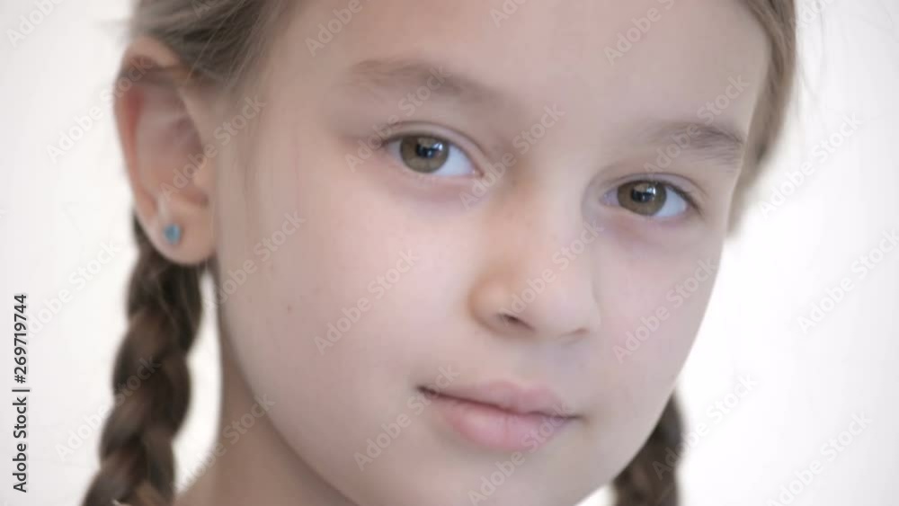 Close-up open look of Caucasian girl with pigtails opening and closing eyes. Neutral emotion look into the camera Close-up open look of Caucasian girl with pigtails opening and closing eyes. Neutral emotion look into the camera