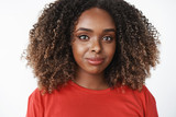 Close-up shot of sincere happy and charismatic african-american woman with afro hairstyle in red casual t-shirt smiling and gazing caring at camera feeling relaxed and patient over white wall