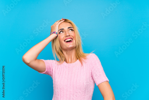 Young blonde woman over blue background laughing © luismolinero