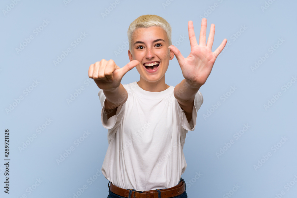 Naklejka premium Teenager girl with white short hair over blue wall counting six with fingers