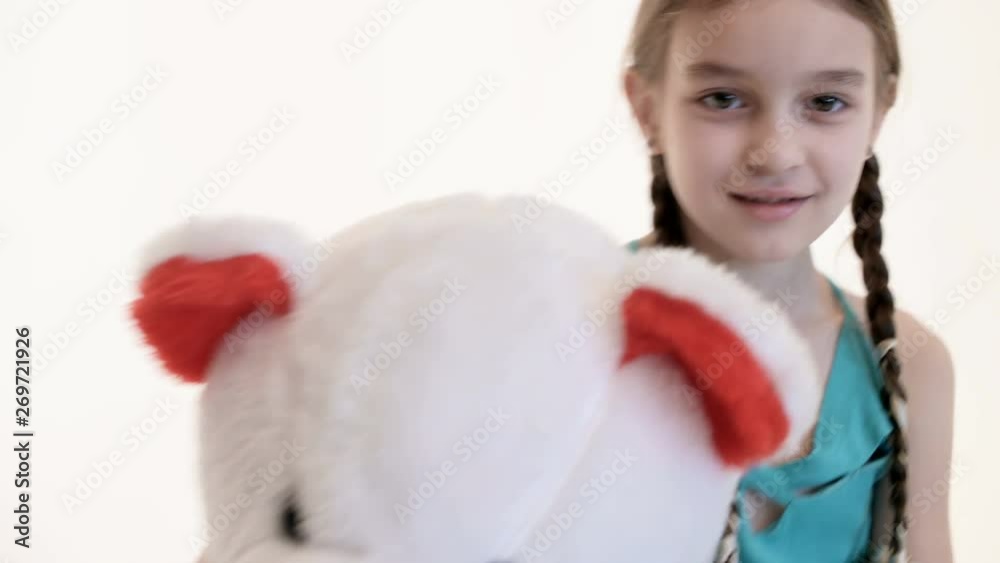 Portrait of a cute white girl with pigtails hugging with a big teddy bear sitting on the floor on a white background in the studio Portrait of a cute white girl with pigtails hugging with a big teddy bear sitting on the floor on a white background in the studio
