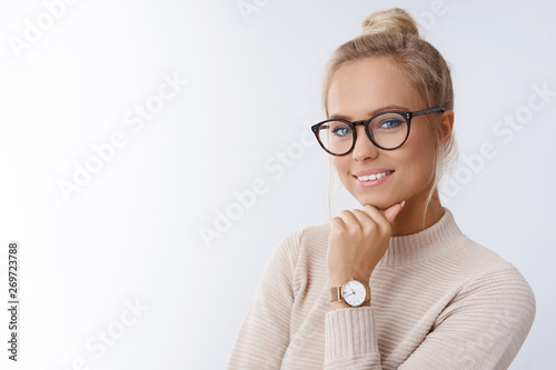 Close-up shot of smiling attractive happy and successful european blond female in sweater watch and glasses grinning expressing confidence, looking accomlished and daring at camera with sassy smile