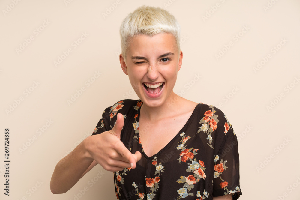 Young woman over isolated wall points finger at you