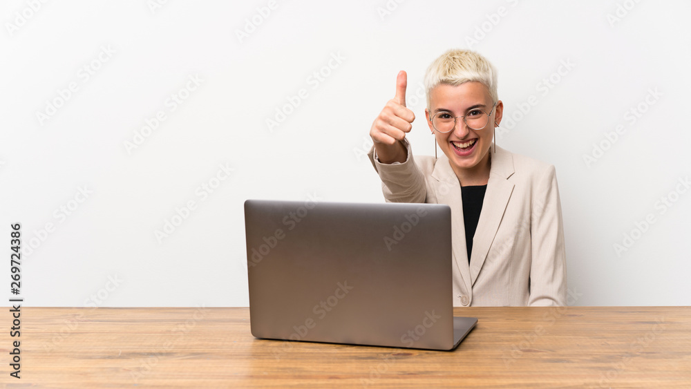 Teenager girl with short hair with a laptop with thumbs up because something good has happened Teenager girl with short hair with a laptop with thumbs up because something good has happened
