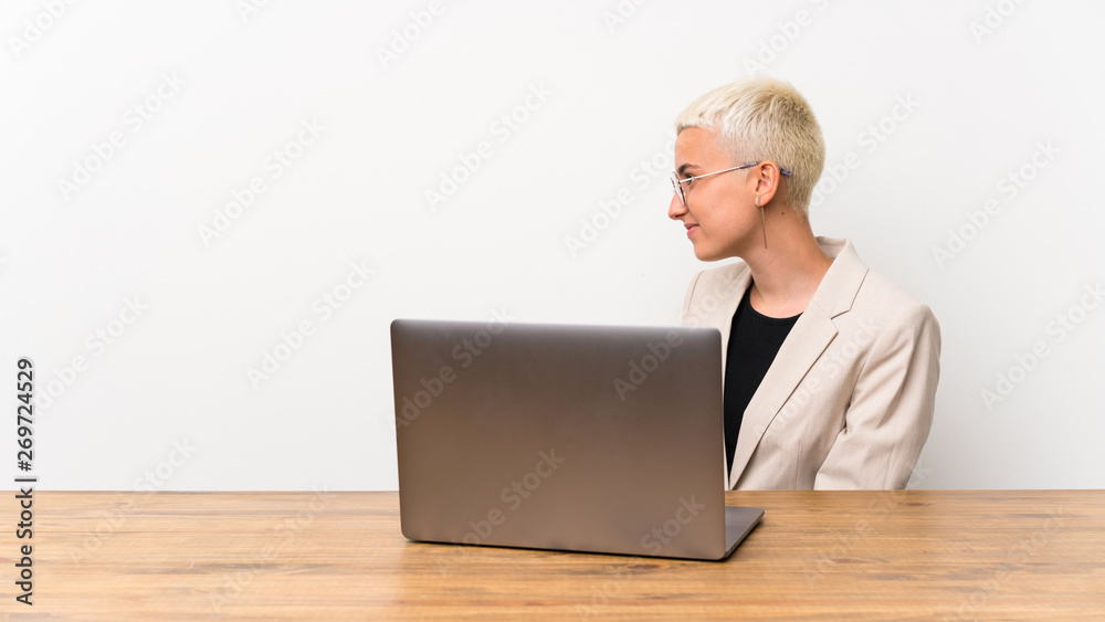 Teenager girl with short hair with a laptop in lateral position Teenager girl with short hair with a laptop in lateral position