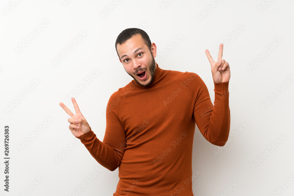 Colombian man with turtleneck sweater showing victory sign with both hands Colombian man with turtleneck sweater showing victory sign with both hands