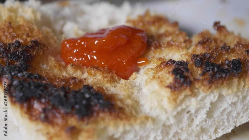 Tomato sauce falling down on a burned toast. Macro slow motion Tomato sauce falling down on a burned toast. Macro slow motion