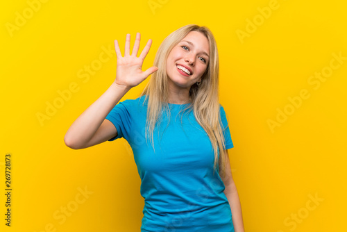 Young blonde woman over isolated yellow background counting five with fingers