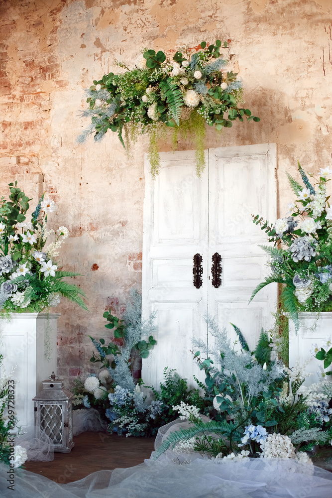 Flower decoration. Wedding decor. Flower interior composition in the studio. Spring photo zone. White doors. 