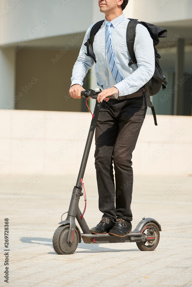 Young office worker with backpack behind his back riding on scooter on the  street outdoors foto de Stock | Adobe Stock