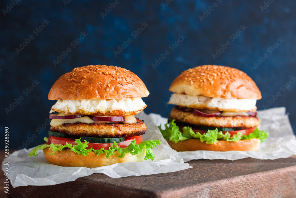 chicken burgers with fried egg cucumber tomato mozzarella cheese lettuce on craft paper chicken burgers with fried egg cucumber tomato mozzarella cheese lettuce on craft paper