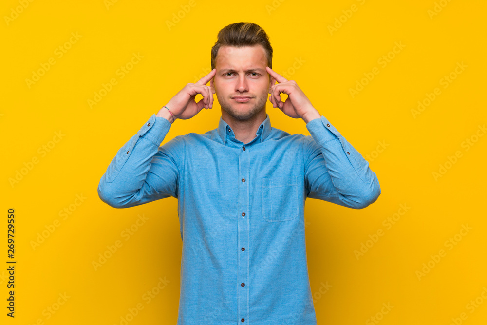 Blonde man over isolated yellow wall having doubts and thinking Blonde man over isolated yellow wall having doubts and thinking