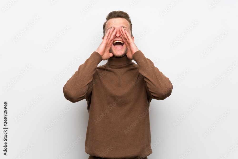 Blonde man over isolated white wall shouting and announcing something Blonde man over isolated white wall shouting and announcing something