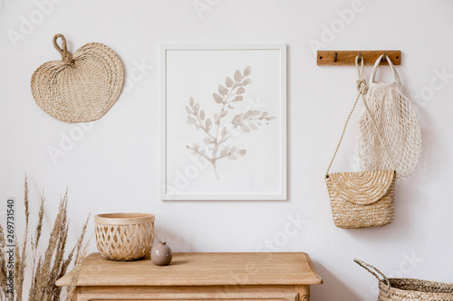 Stylish korean interior of living room with brown mock up poster frame, elegant accessories, flowers in vase, wooden shelf and hanging rattan leaf, bags. Minimalistic concept of home decor. Template. 