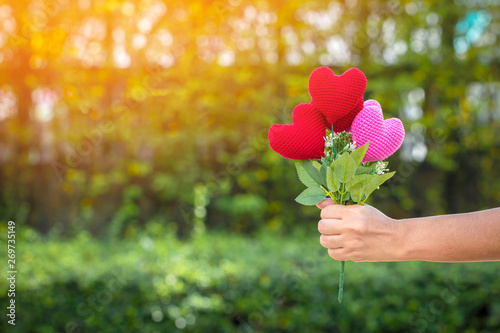фотографія Woman hand holding a flower of heart on sunlight in the public park, for give supporting when people get who lack of desire with love concept