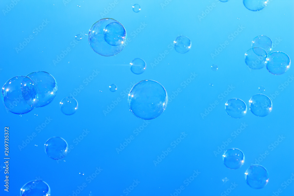 Many large soap bubbles flying in blue sky, city magic