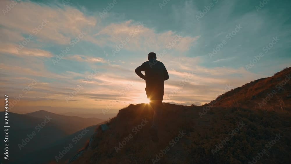 The man jumping on the mountain against the beautiful sunset. slow motion