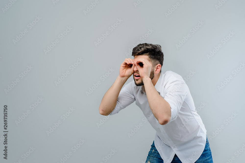 young man looking for something isolated over grey background young man looking for something isolated over grey background
