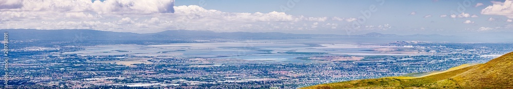 Panoramic view of the cities on the shoreline of south San Francisco bay area; colorful salt ponds in the background; Silicon Valley, California