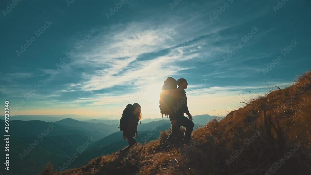 The couple with camping backpacks walking to the mountain top. slow motion