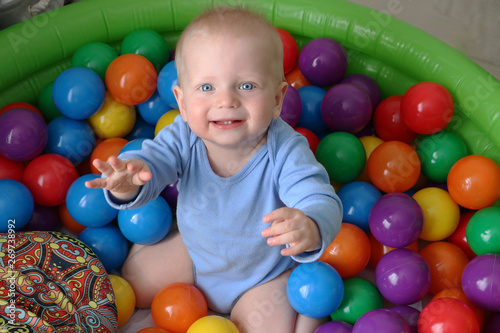 One year old baby boy is playing in ball pool on safety playground. Having fun with  toys