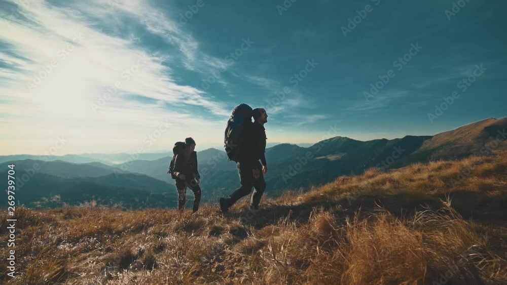 The couple walking on the mountain on a sunny background. slow motion