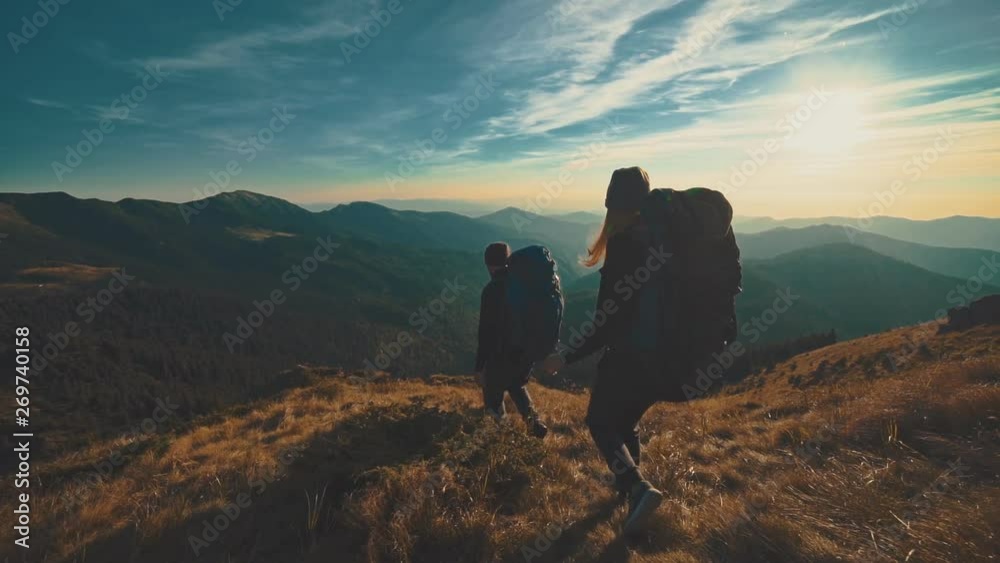 The man and woman walking in the mountain on the sunset background. slow motion