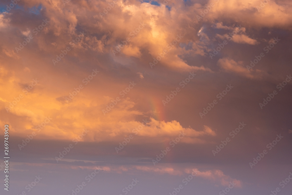 Sunset clouds with orange light and rainbow