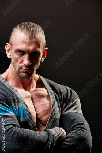 Sport concept. Fitness athlete with perfect muscles poses on camera over black background.